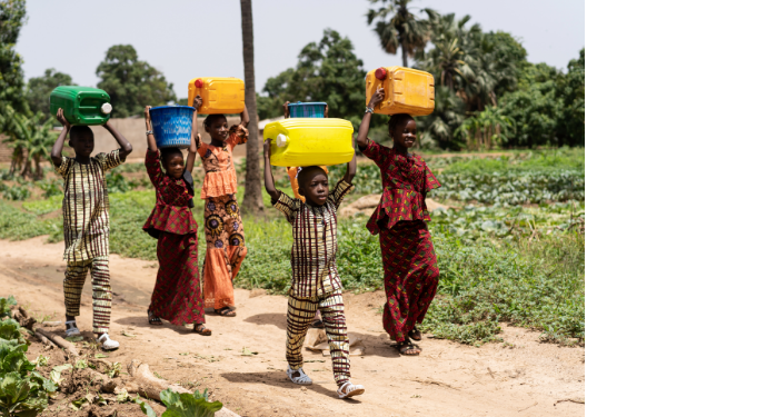 Women and children walking with water containers in a rural community, highlighting the economic and social burden of limited water access.